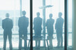 Photo: Silhouette of business people in a row looking out office window Silhouette of business people in a row looking out office window
