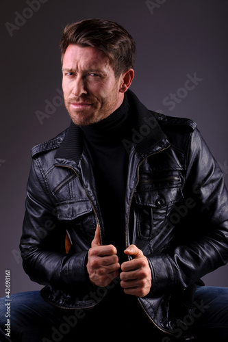 Photo: handsome man in leather jacket seated handsome man in leather jacket seated