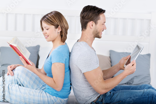 Foto: paar mit buch und tablet-pc sitzt im bett paar mit buch und tablet-pc sitzt im bett