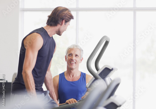 Photo: Men talking on treadmill in gymnasium Men talking on treadmill in gymnasium