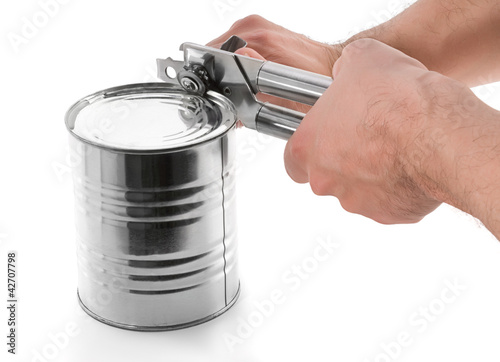 Photo: Opening tin with can opener isolated on white background Opening tin with can opener isolated on white background