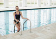 Portrait of smiling woman standing on ladder in swimming pool