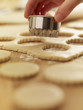 Hand holding cookie cutter over dough