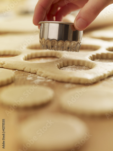 Photo: Hand holding cookie cutter over dough Hand holding cookie cutter over dough
