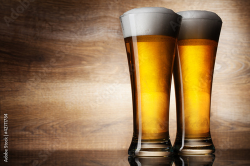 Photo: Two glass beer on wood background with copyspace Two glass beer on wood background with copyspace