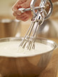 Woman whisking cream with egg beater