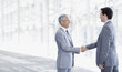 Smiling businessmen shaking hands in modern corridor