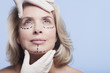 Rubber-gloved hands holding womanís face with dotted lines