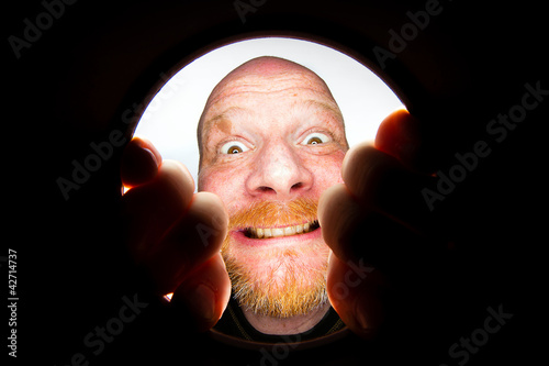 Photo: Funny bald man looking down a hole Funny bald man looking down a hole