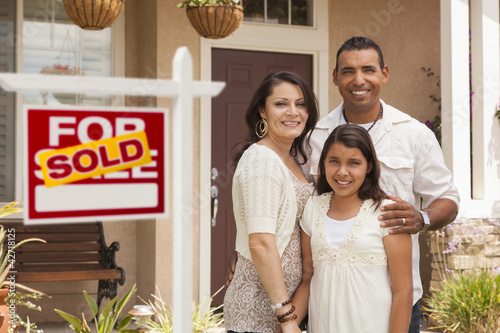 Photo: Hispanic Family in Front of Their New Home with Sold Sign Hispanic Family in Front of Their New Home with Sold Sign