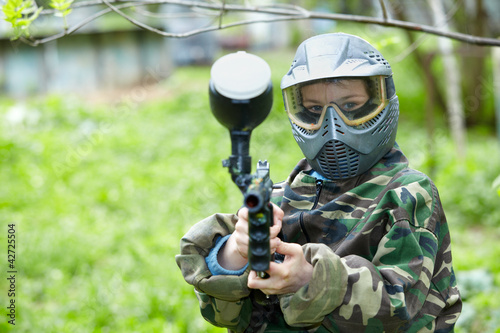 Photo: Paintball player in camouflage uniform and protective mask poses Paintball player in camouflage uniform and protective mask poses