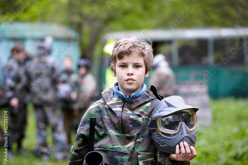 Photo: Boy in camouflage holds paintball gun barrel up in one hand Boy in camouflage holds paintball gun barrel up in one hand