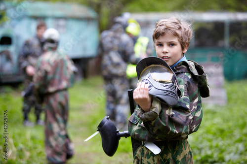 Photo: Boy in camouflage holds paintball gun barrel up in one hand Boy in camouflage holds paintball gun barrel up in one hand