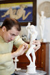 Sculptor works with concentration in studio on plaster sculpture