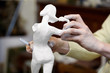 Hands of sculptor works with plaster statuette.