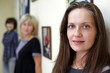 Three women stand near the wall, focus on the face of the first