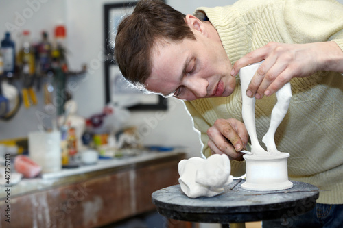 Photo: Sculptor works in studio on fragment of plaster sculpture. Sculptor works in studio on fragment of plaster sculpture.