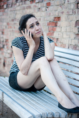 Photo: Unhappy young woman crying while talking on the phone Unhappy young woman crying while talking on the phone