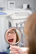 Frau schaut in den Spiegel beim Zahnarzt