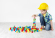 Foto: builder boy in helmt playing with toys blocks, building city builder boy in helmt playing with toys blocks, building city