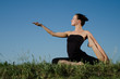 Photo: Yoga woman on green grass. Sky background. Yoga woman on green grass. Sky background.