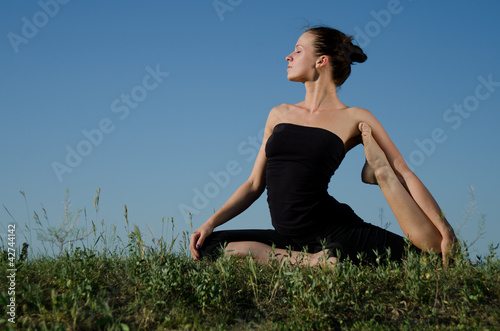 Photo: Yoga woman on green grass. Sky background. Yoga woman on green grass. Sky background.