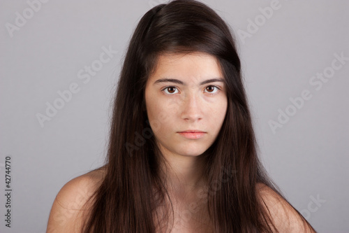 Photo: Pretty girl looking at you over a grey background Pretty girl looking at you over a grey background