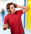 portrait of young man listening music and holding beer indoor