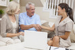 Saleswoman Shaking Hands With Senior Couple at Home
