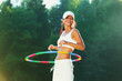 woman rotates hula hoop on nature background