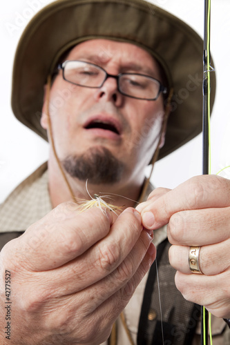 Photo: Fly fisherman threading line through hook. Fly fisherman threading line through hook.