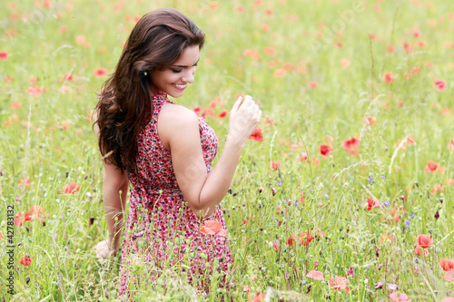 Photo: Jeune femme en robe fleurie dans un champ de coquelicot Jeune femme en robe fleurie dans un champ de coquelicot