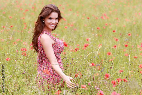 Foto: Jeune femme en robe fleurie dans un champ de coquelicot Jeune femme en robe fleurie dans un champ de coquelicot