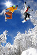 Snowboarders jumping against blue sky