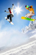 Snowboarders jumping against blue sky