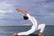 young Asian man doing yoga on the beach