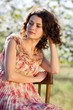 Photo: Beautiful woman sits on a chair in a spring garden Beautiful woman sits on a chair in a spring garden