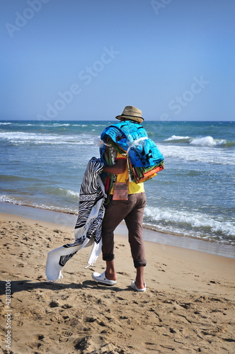 Photo: Venditore ambulante di tappeti cammina lungo la spiaggia Venditore ambulante di tappeti cammina lungo la spiaggia