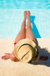Woman sitting in a swimming pool with a sunhat
