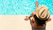 Woman sitting in a swimming pool with a sunhat