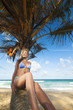 Foto: Young woman sitting on the palm tree. Vertical shot. Young woman sitting on the palm tree. Vertical shot.