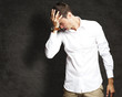 Photo: Angry young man doing frustration gesture against a grunge wall Angry young man doing frustration gesture against a grunge wall