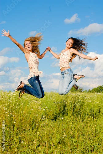 Foto: Two happy young women jumping Two happy young women jumping
