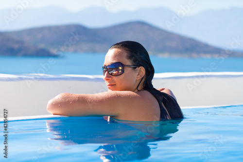 Foto: Young woman relaxing at swimming pool of Greece Young woman relaxing at swimming pool of Greece