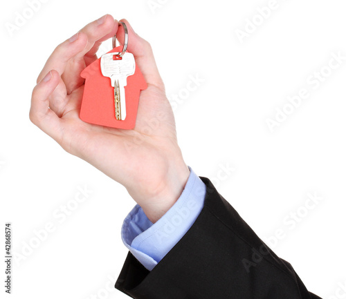 Photo: Key with house-shaped charm in hand isolated on white Key with house-shaped charm in hand isolated on white