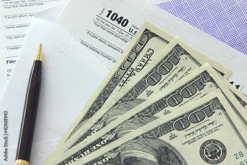 Photo: Tax papers with 100 dollar bills Tax papers with 100 dollar bills