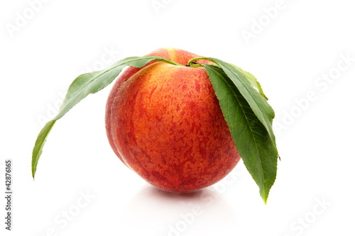 Photo: Ripe peach with green leaves. Ripe peach with green leaves.
