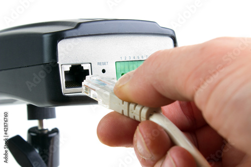 Photo: Hand inserting ethernet cable into network camera Hand inserting ethernet cable into network camera