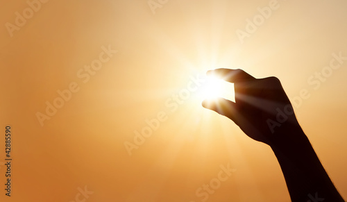 Foto: Male hand catching the sun at sunset with copy space Male hand catching the sun at sunset with copy space