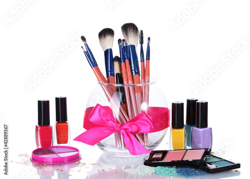 Photo: make-up brushes in glass vase and cosmetics isolated on white make-up brushes in glass vase and cosmetics isolated on white